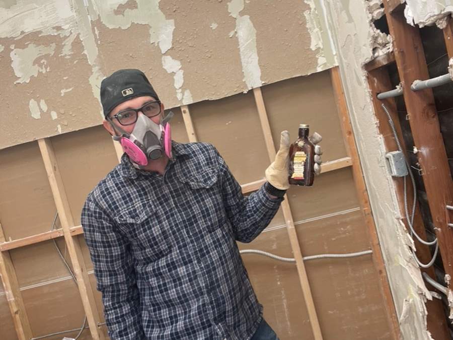 man with construction mask and bottle of bourbon