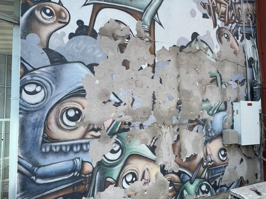 mural being scraped off wall 