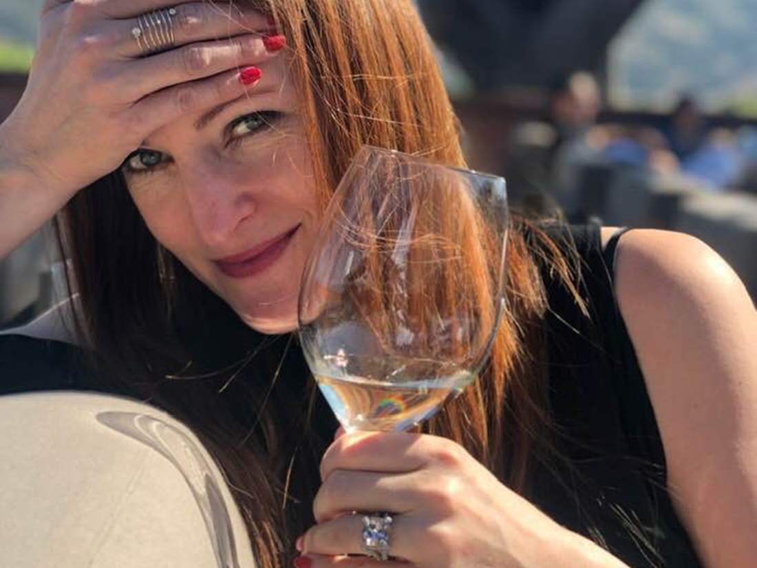 Red haired lady with almost empty glass of white wine. 