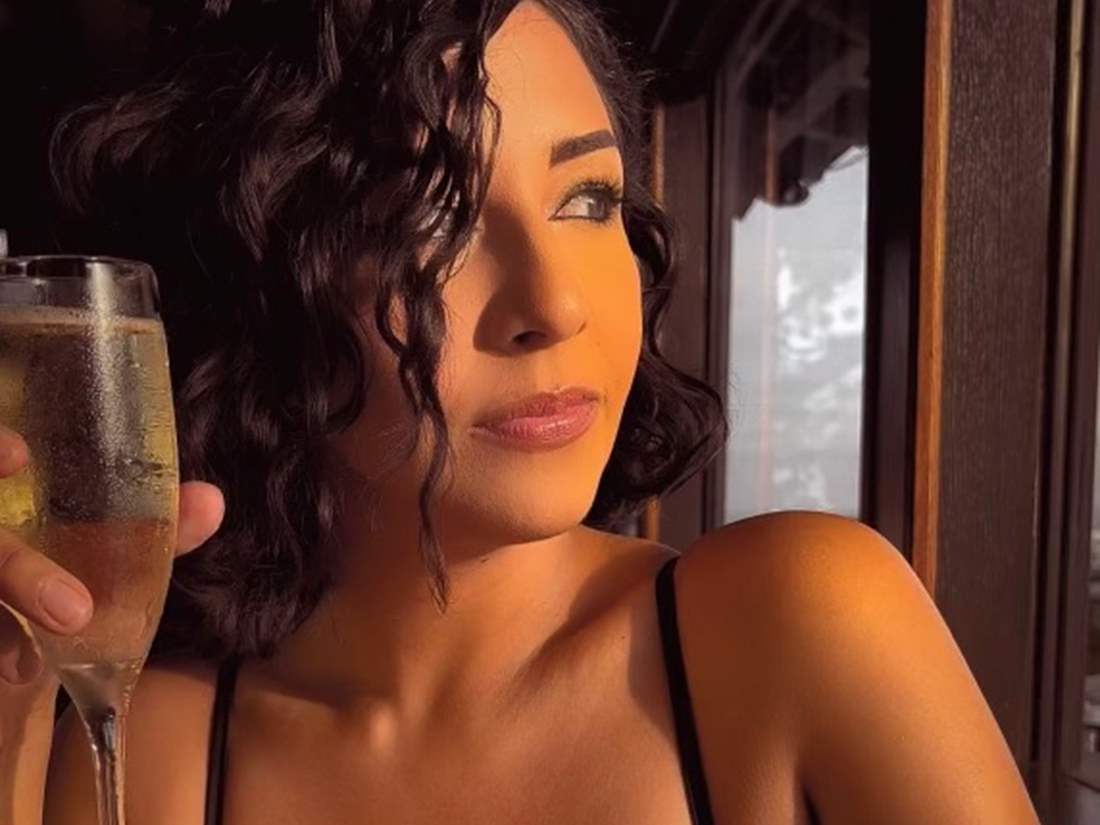 Beautiful woman with brown curly hair and a glass of champagne